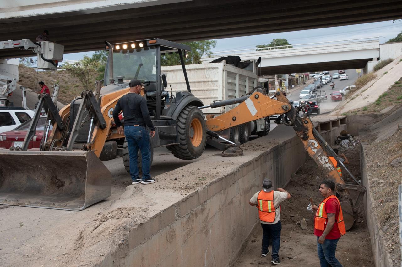 Retro excavadora en una calle y haciendo limpieza junto a trabajadores