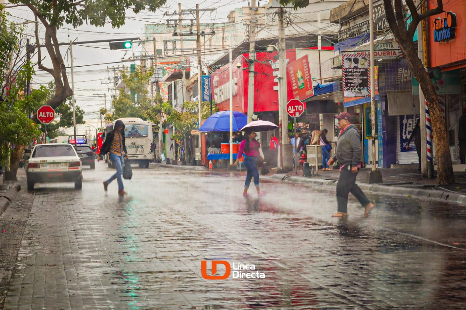 Personas caminando y cruzando una calle en medio de la lluvia