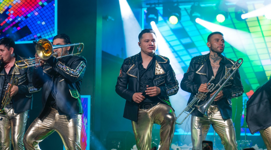 Integrantes de Banda Los Recoditos cantando en un escenario junto con su vocalista Rafa González
