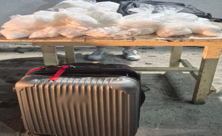 Mesa con bolsas que contienen una sustancia de color blanco y una maleta de color plata