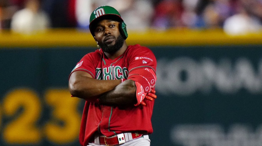 jugador de béisbol con los brazos cruzados usando una casaca roja y gorra verde