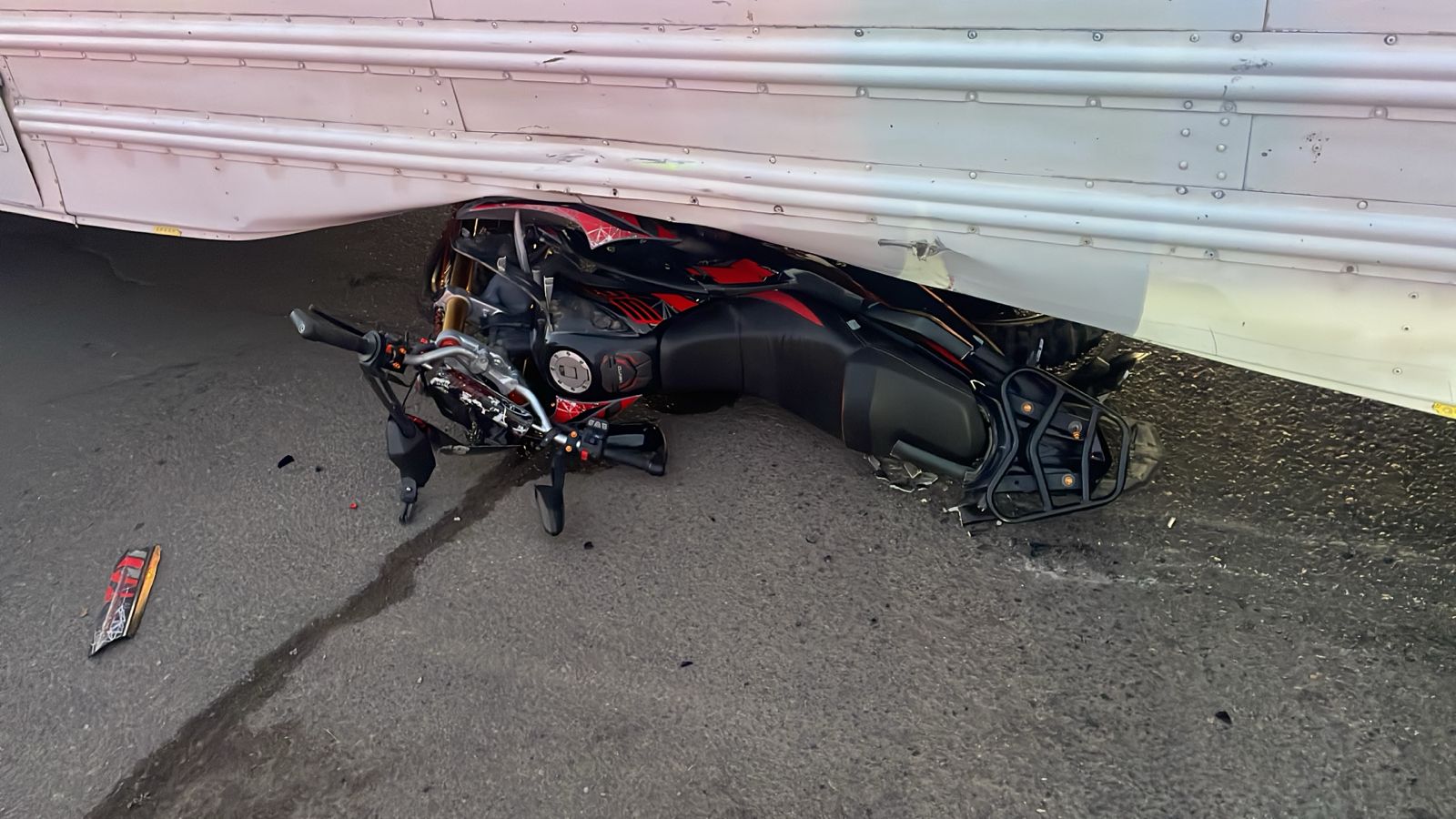 motocicleta abajo de un camión color blanco luego de un accidente