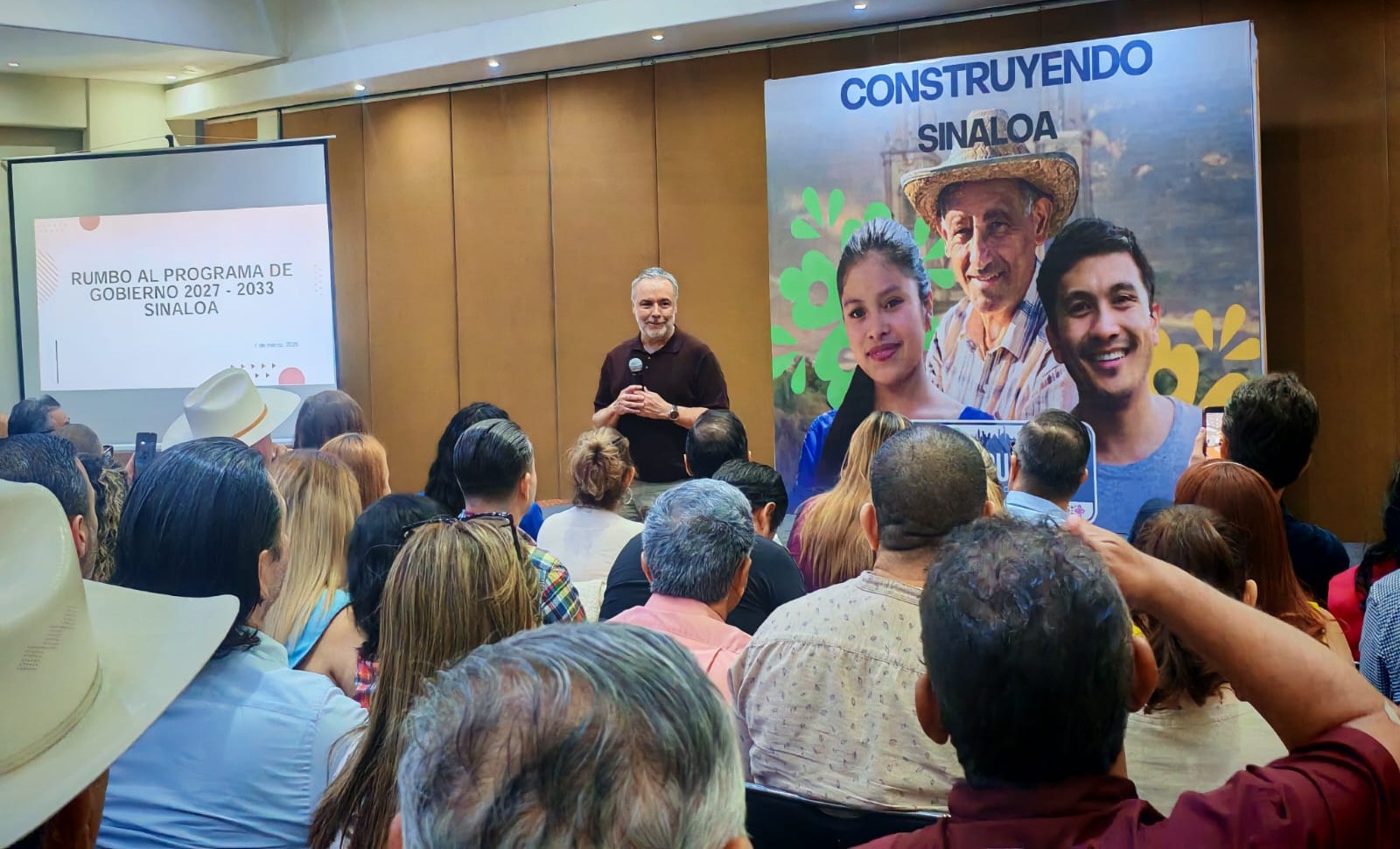 Conferencia, persona al frente hablado con micrófono en mano