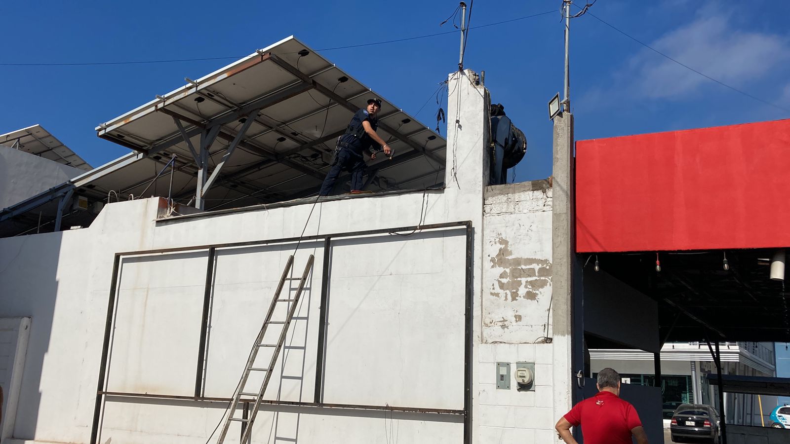 Persona arriba de un lugar con una manguera y una escalera en una barda