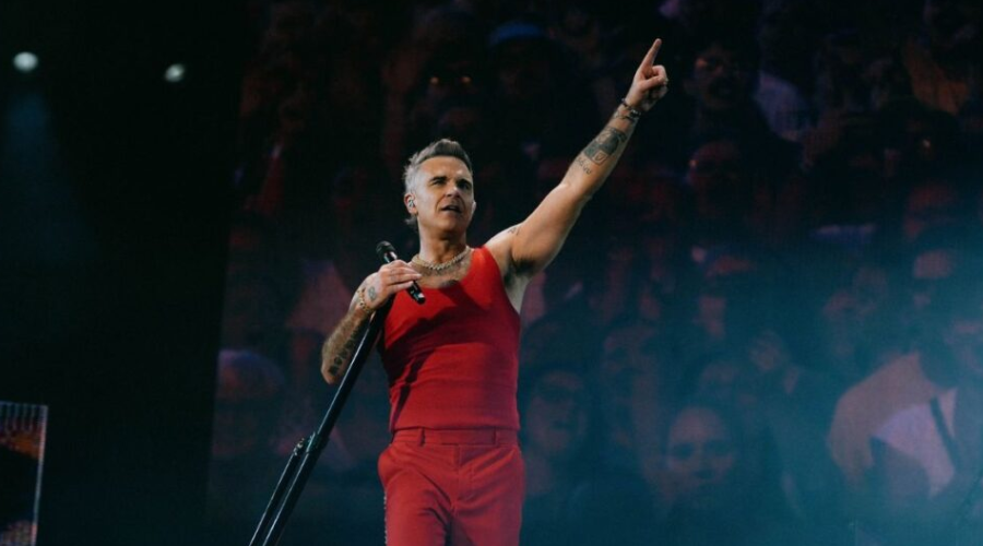 Robbie Williams en un escenario con un micrófono en mano
