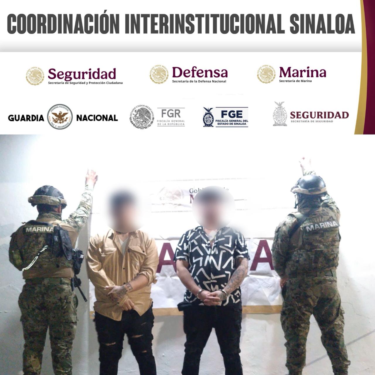 elementos de la marina dando la espalda a la cámara con dos personas detenidas con rostro difuminados