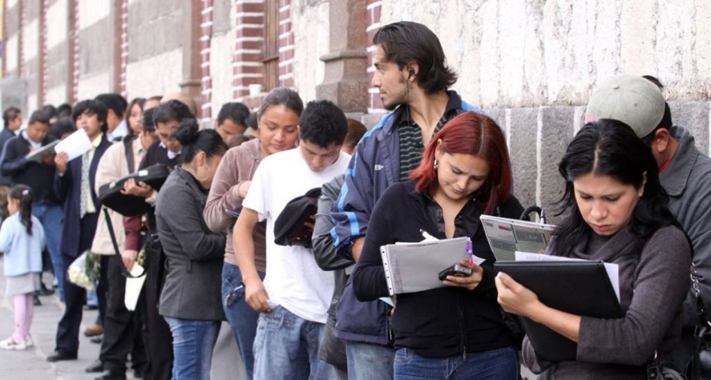 personas en una fila escribiendo en unas hojas