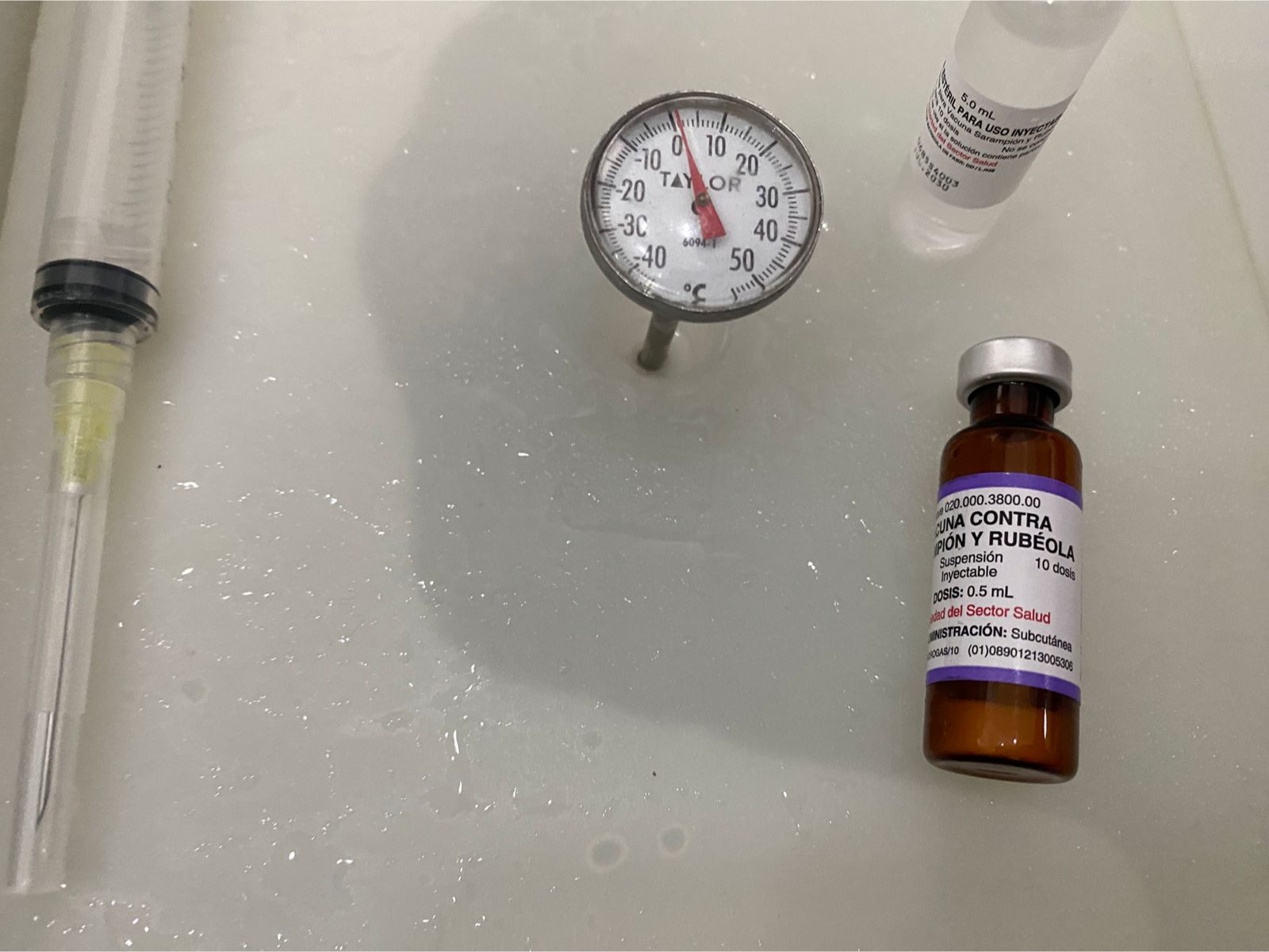 Botella con medicina para el sarampión y rubéola y una inyección