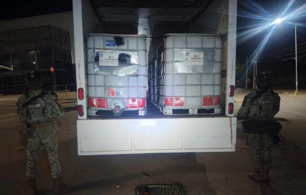Elementos del Ejército Mexicano afuera de un vehículo con las puertas traseras de una caja abiertas y bidones dentro del vehículo