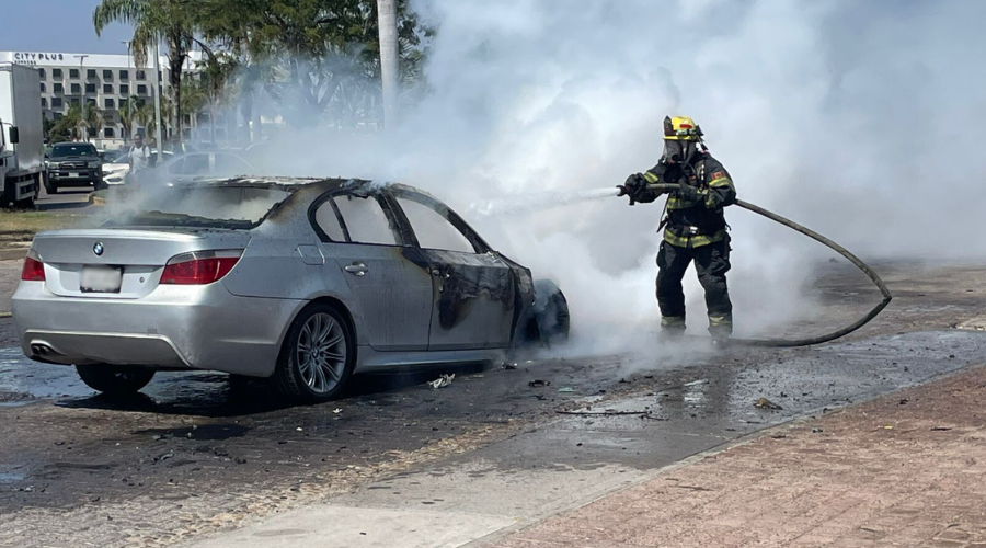 Bombero rocía con agua a vehículo incendiado