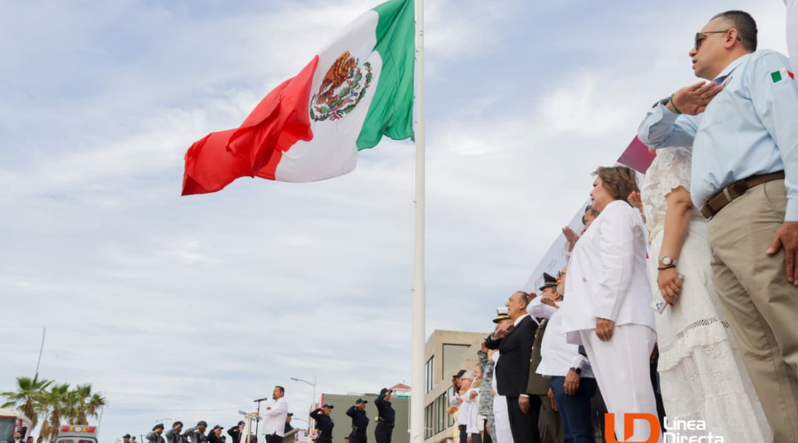 Bandera de México ondeando en lo alto y personas en una formación