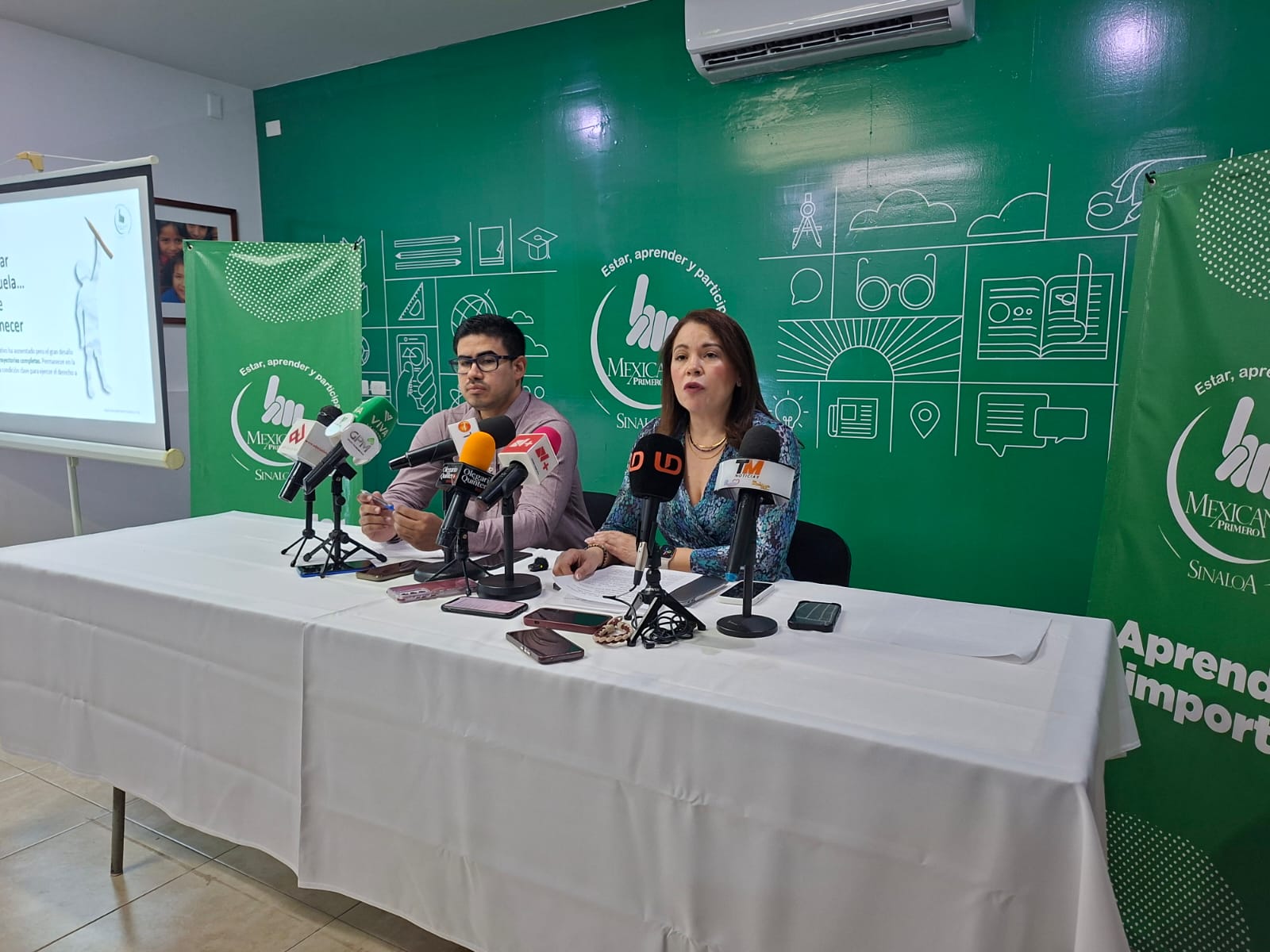 Dos personas en conferencia de prensa junto a micrófonos de los medios de comunicación