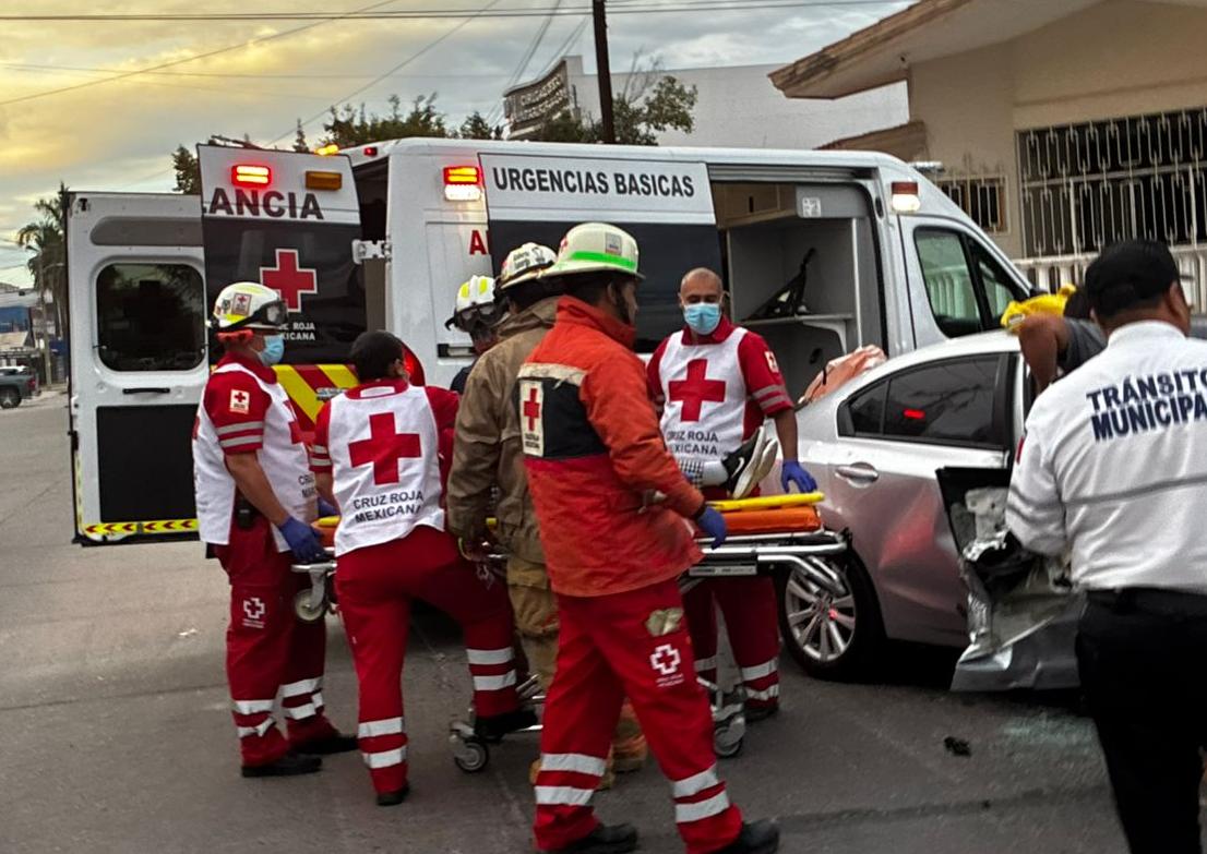 Paramédicos de la cruz roja con una camilla junto a un carro chocado en Los Mochis