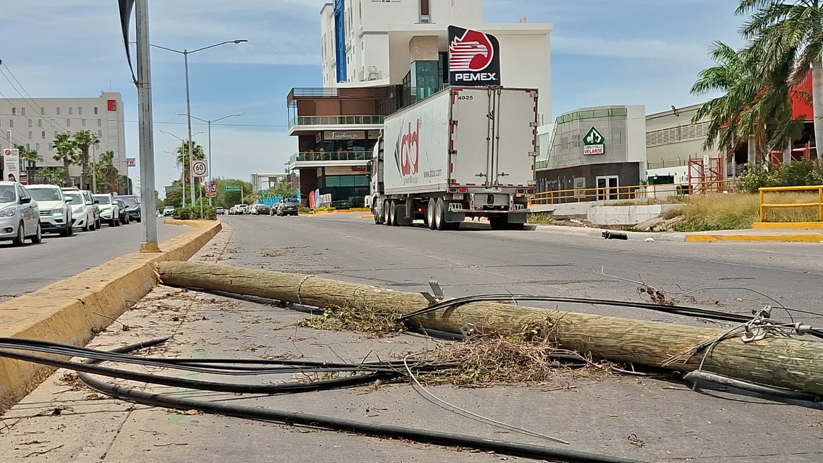 Poste de luz en el suelo de una calle transitada en el fondo un tráiler