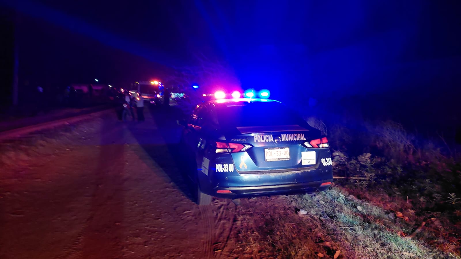 Unidad policiaca con las luces encendidas en el acotamiento de una carretera