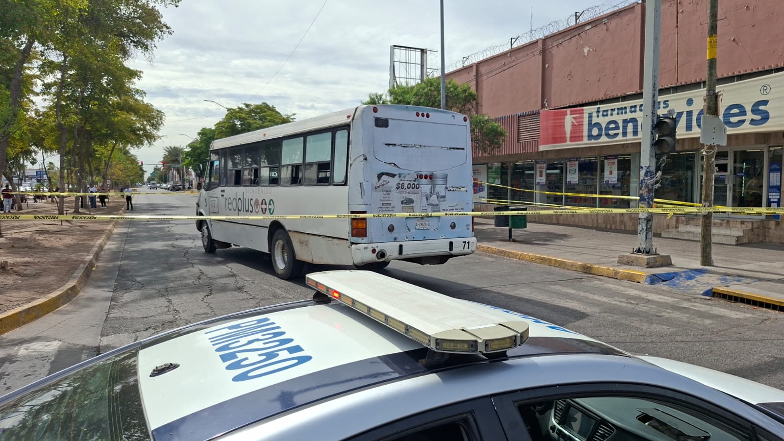 Parte de arriba de una patrulla y al fondo un camión urbano delimitado con cinta amarilla en zona centro de Los Mochis