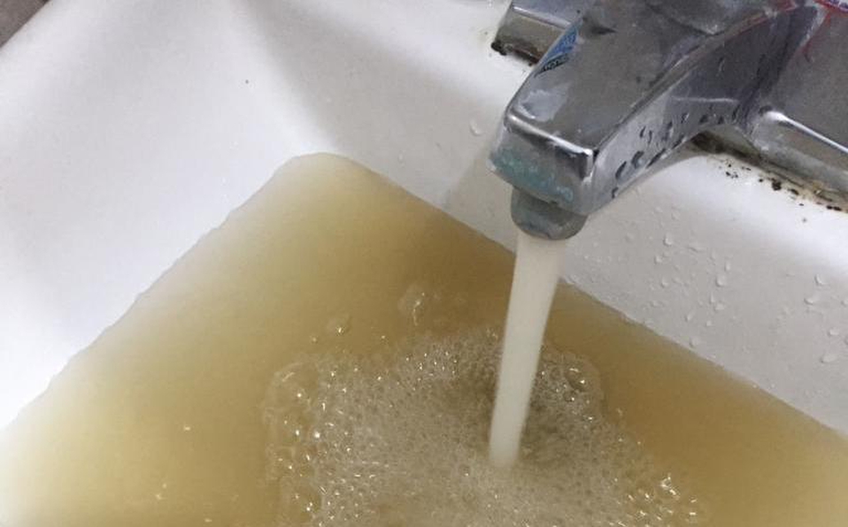 Llave de agua sacando agua color café