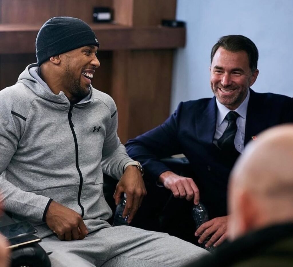 Anthony Joshua y Eddie Hearn sentados sonriendo