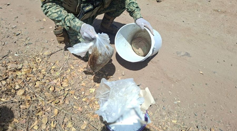 Elemento del ejercito sosteniendo una cubeta y una bolsa con contenido de droga