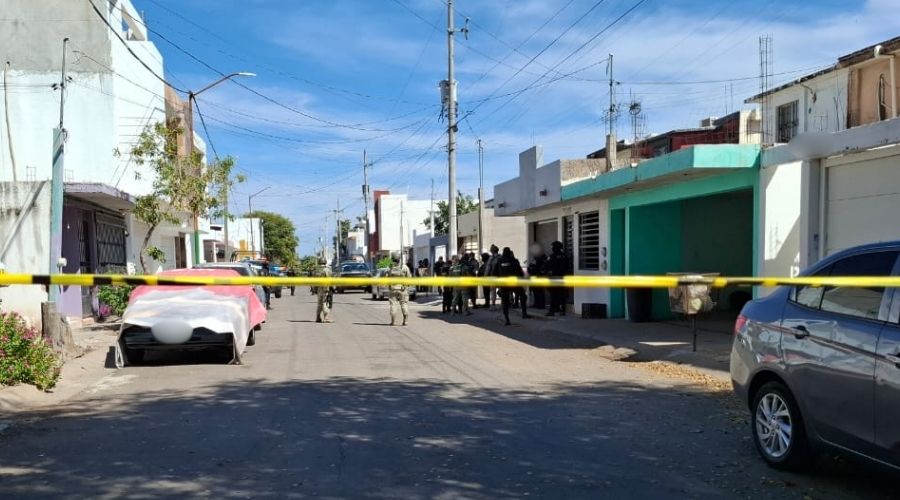 Cinta amarilla de precaución con elementos de seguridad al fondo en una casa junto a una camioneta de la policía