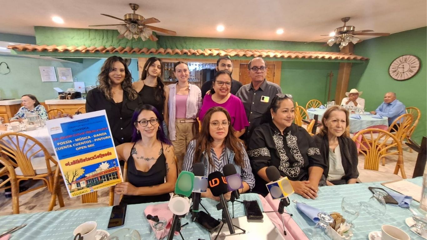 Personas sentadas y de pie detrás de mesa con micrófonos