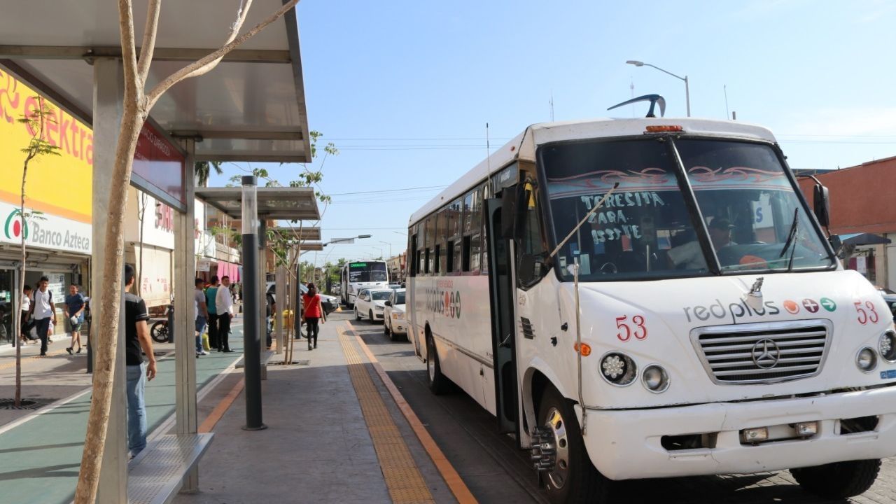 Parada de camiones urbanos, donde se ve transporte público estacionado y personas abordando
