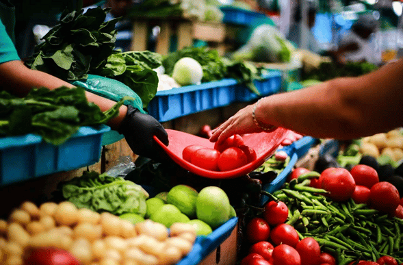 Verduras y frutas organizadas en jabas, y persona seleccionando