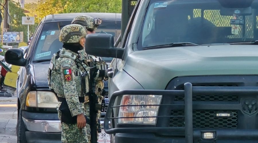 Dos elementos del ejército mexicano con una camioneta en color verde