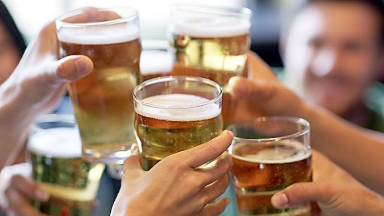 Personas colocando vasos con cerveza en el medio a manera de brindis