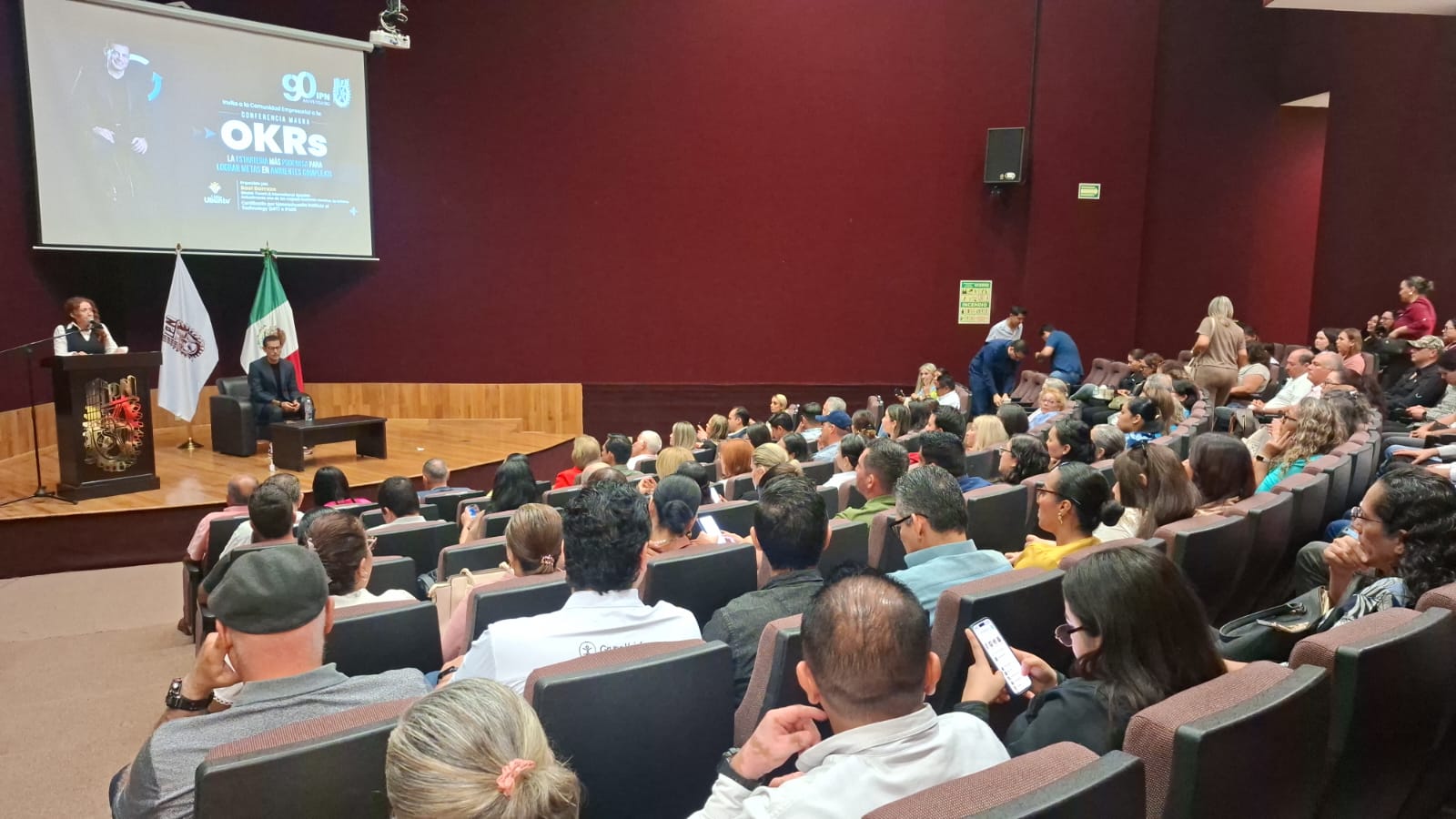 Auditorio con personas y frente a ellos Sael Barraza con una proyección