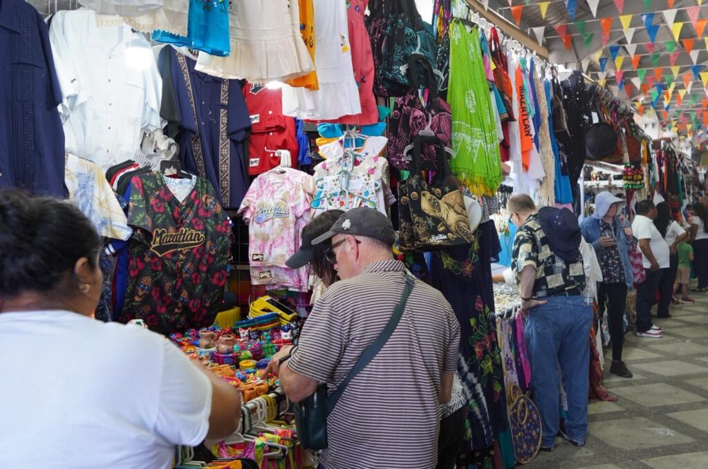 Personas comprando ropa y recuerdos en mercado de Mazatlán