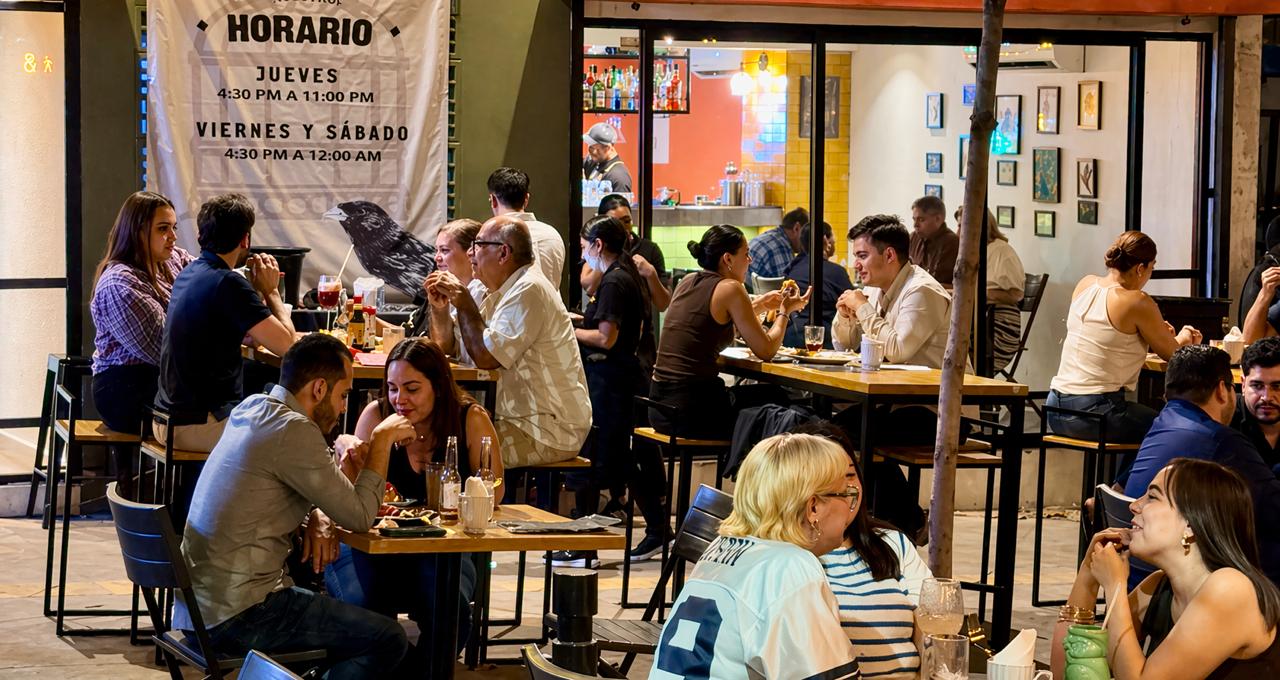 Personas en la noche sentadas en la mesa y sillas de un restaurante