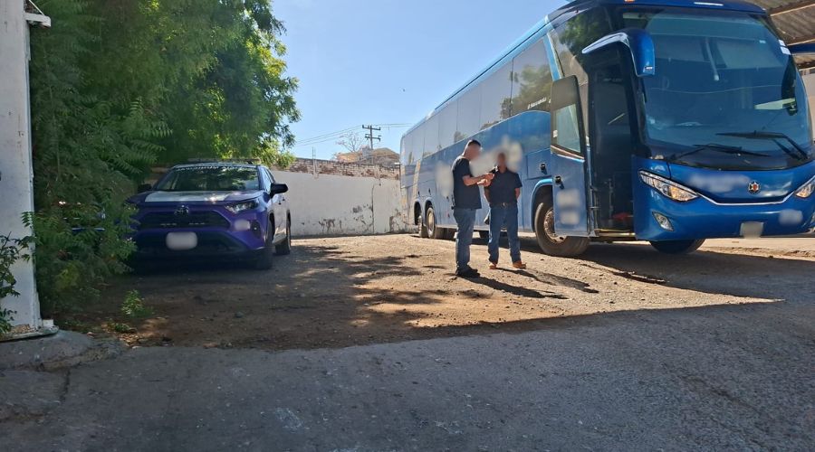 Unidad de la policía municipal de Guasave junto a un autobús en una zona y dos personas