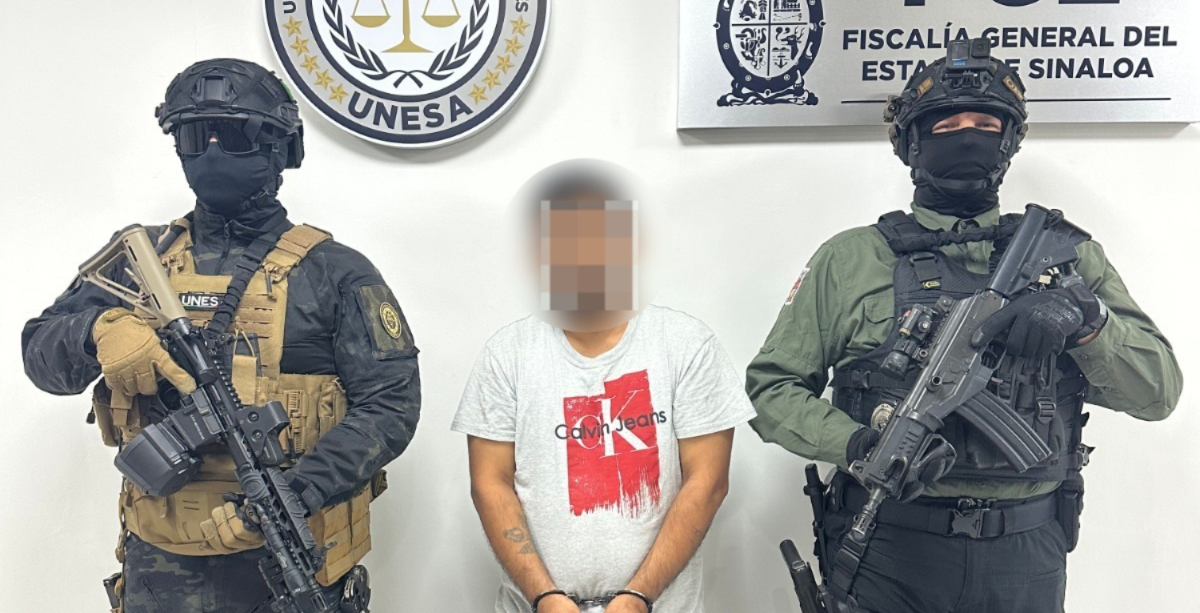 Dos elementos de seguridad junto a una persona detenida con la cara difuminada y el logo de la FGE