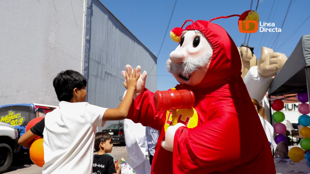 Doctor Simi con traje del chapulin colorado junto a un niño chocando las manos