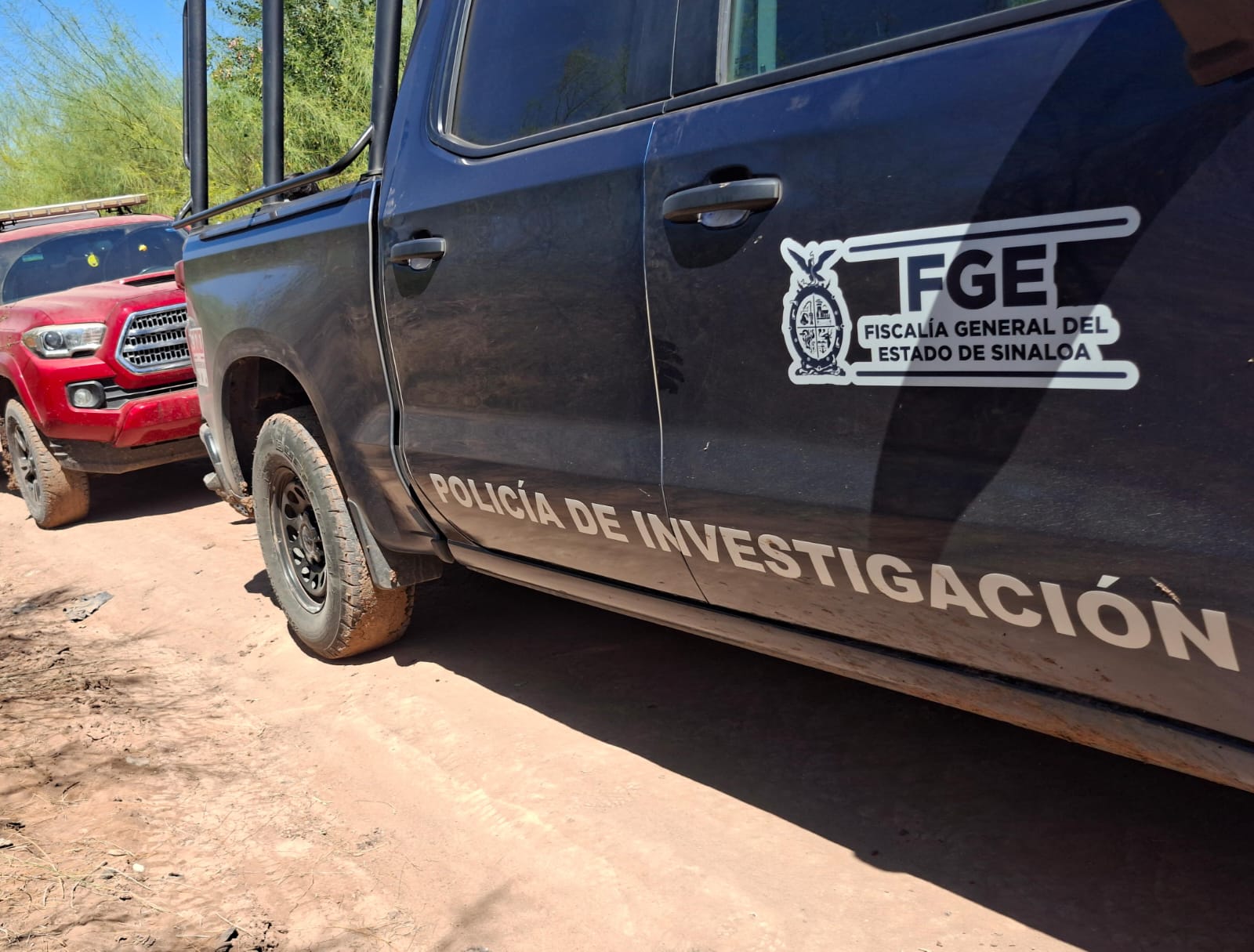 Unidad de la FGE en un camino de terracería y al fondo una camioneta de color rojo
