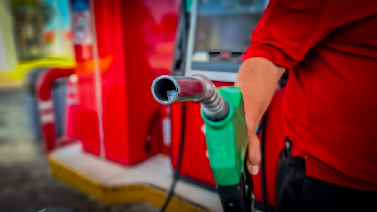 Mano de una persona sosteniendo una manguera dispensadora de color verde