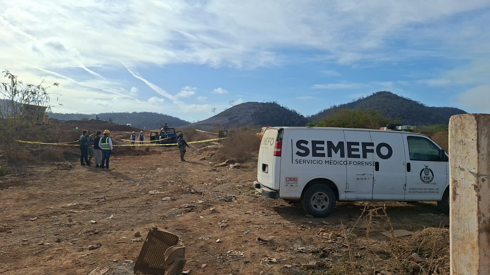 Terreno llano donde se ve una unidad de Semefo y elementos de seguridad asegurando el área