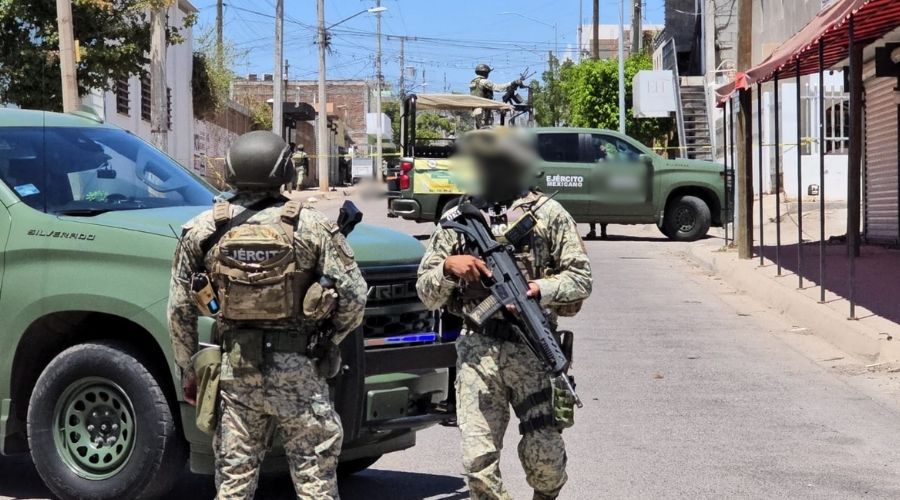 Dos camionetas del ejército mexicano con dos agentes con armas en la calle