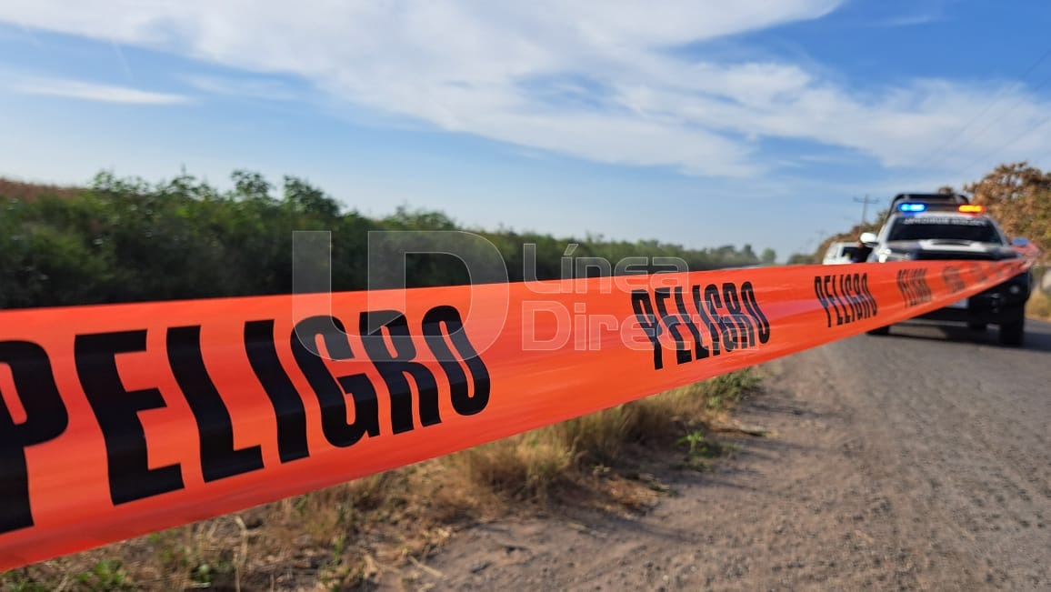 Cinta roja con la leyenda de peligro junto a una camioneta de la policía
