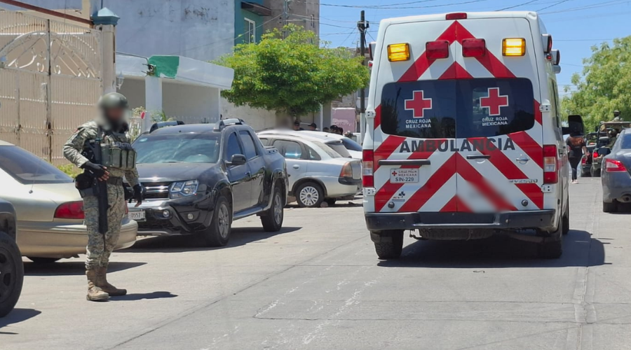 Una ambulancia de la cruz roja en el medio de la calle junto a un elemento del ejército mexicano