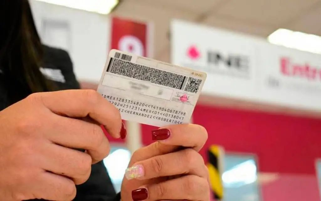 Persona con sus dos manos agarrando su credencial INE