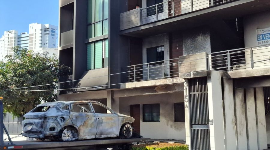 Edificio con notables quemaduras y vehículo dañado sobre una grúa