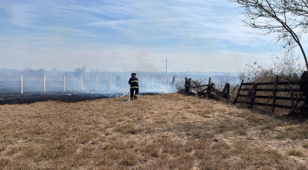 Bomberos combatiendo el incendio en el terreno.