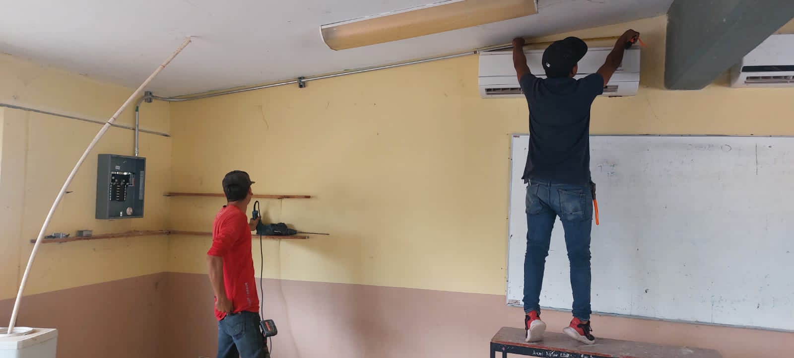 Personal de mantenimiento realizando trabajos en aula y con aire acondicionados