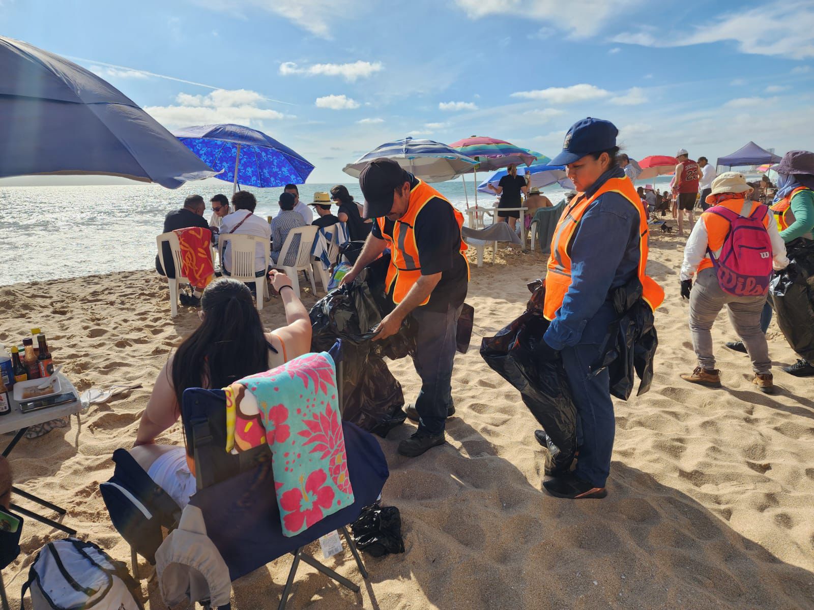 personas limpiando playa con bolsa de basura