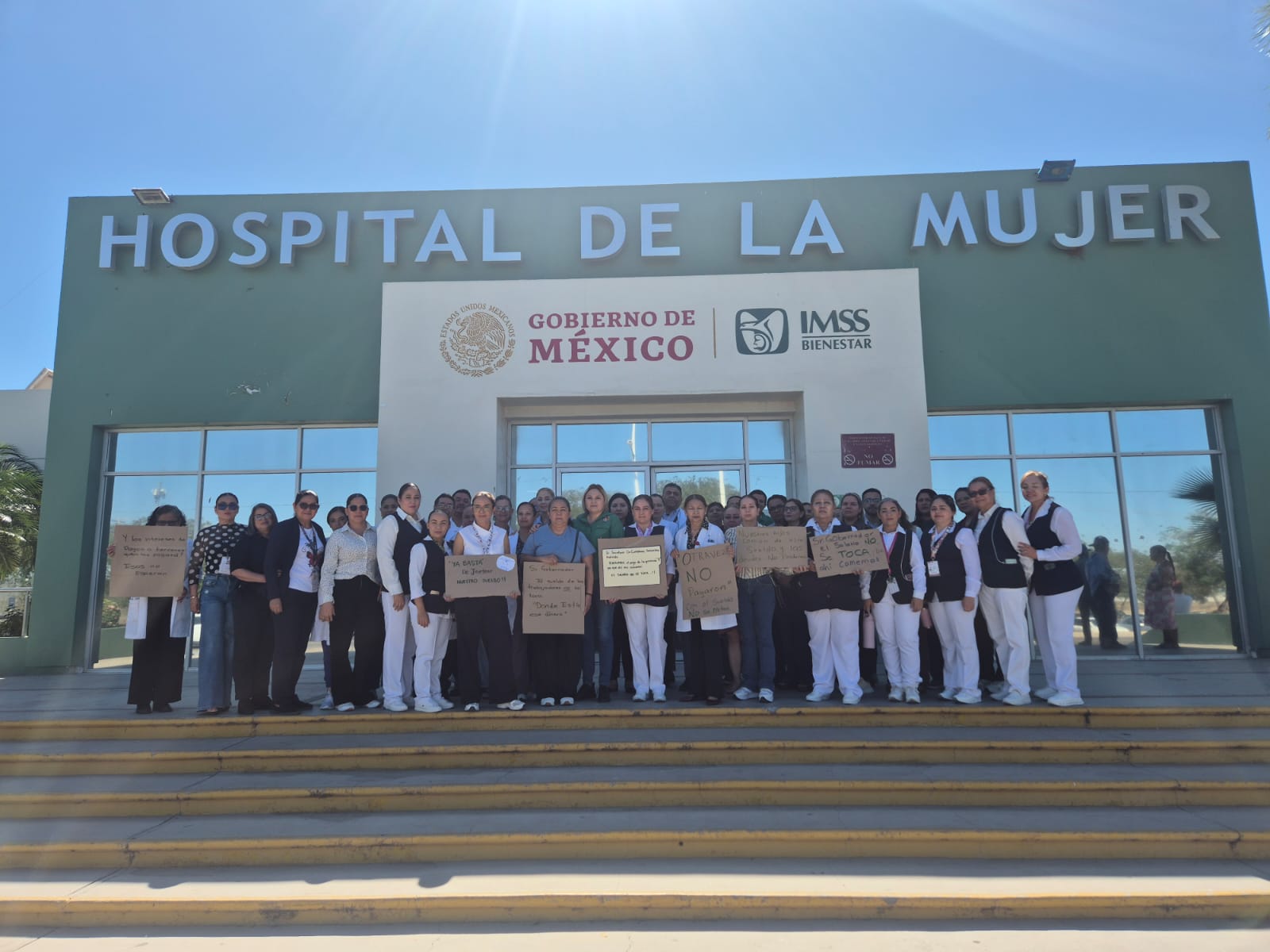 Personas afuera de un hospital con pancartas en una manifestación