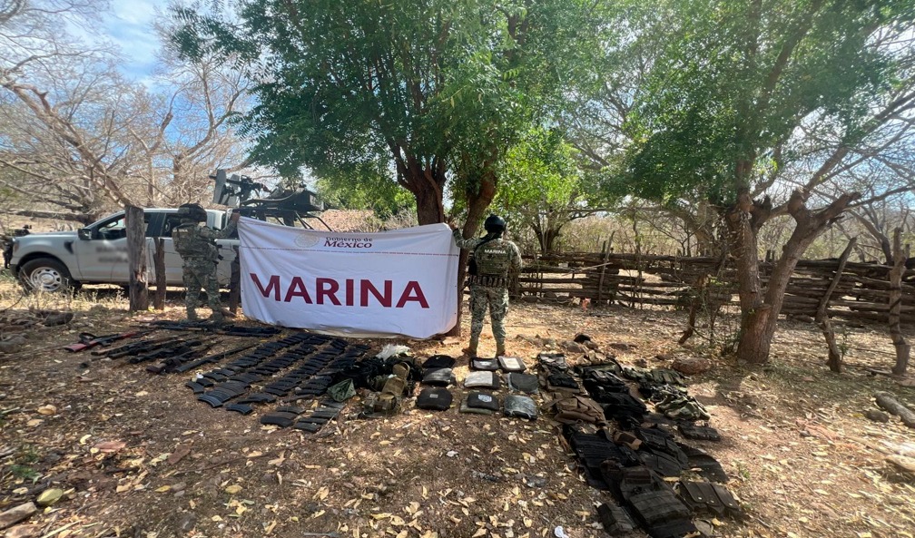 Elementos de la marina de espaldas sosteniendo una pancarta y debajo de ellos artefactos asegurados en operativo
