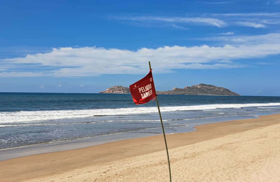 Banderín rojo en playa de Mazatlán.