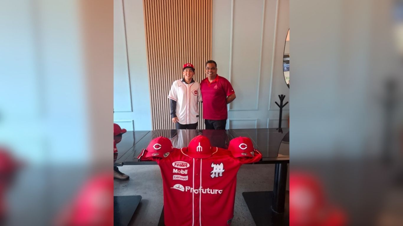 Mikel Nieblas tomándose foto con persona, playera roja enrente y gorras rojas